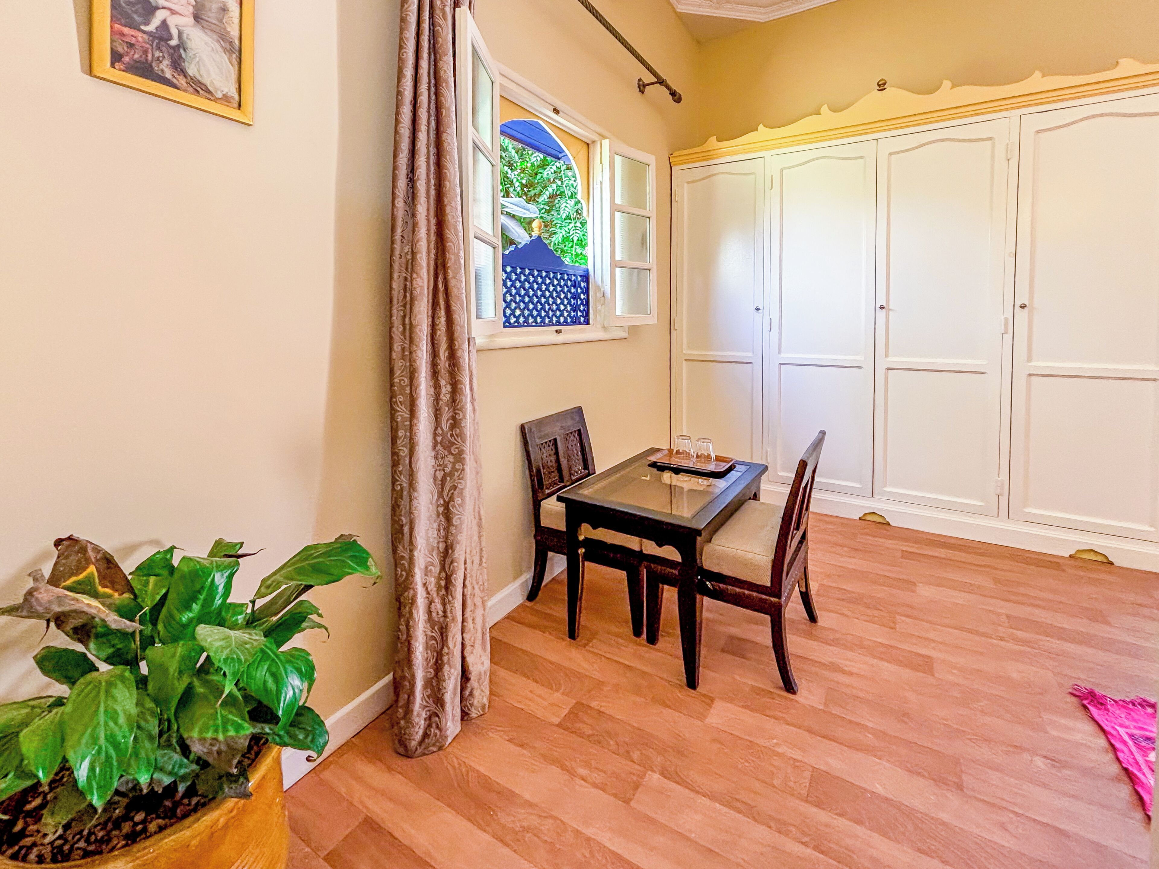 Un coin repas avec une table et des chaises, une fenêtre donnant sur un beau paysage et une armoire.
