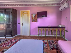 Una habitación con cama, escritorio, televisor y armario.