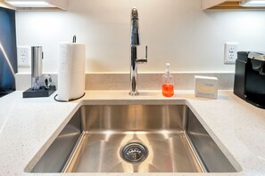 A modern kitchen with a stainless steel sink, a paper towel dispenser, a soap dispenser, and a coffee machine. - Large Studio - Nearby Parking - Hospitals - 3F (Louisville)