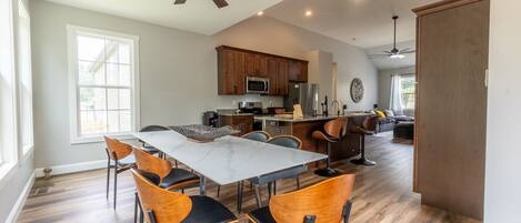 A spacious kitchen with a dining area, wooden cabinets, and a ceiling fan.