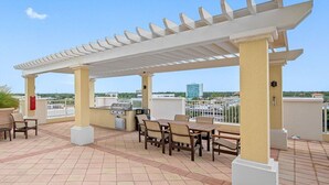 Un patio exterior con pérgola, asientos y una parrilla.