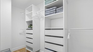 Un armario blanco con varios estantes y cajones, algunos con toallas dobladas.