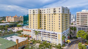 A multi-story hotel with a yellow facade, multiple balconies, and a parking garage. - Station Square Condominiums – Spacious Downtown Clearwater Retreat with Resort-Style Amenities (Clearwater)