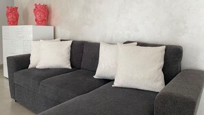 A grey sofa with white patterned cushions, a white side table with red sculptures, and a textured wall. - Arricriati Near Ortigia by Wonderful Italy (Syracuse)