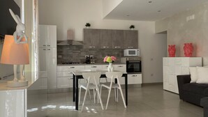 A modern kitchen with white cabinets, a dining table with chairs, a microwave, and an oven. - Arricriati Near Ortigia by Wonderful Italy (Syracuse)