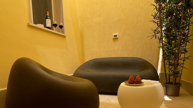 A modern interior with two dark-colored sofas, a small white table with decorative items, and a potted plant. - Arricriati Near Ortigia by Wonderful Italy (Syracuse)