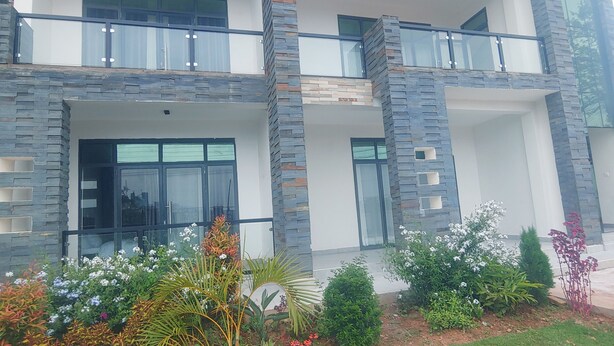 Un edificio moderno de dos plantas con fachada de piedra, ventanas grandes y un balcón.