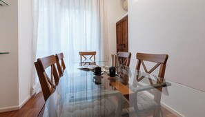 Een eetgedeelte met een glazen tafel, houten stoelen en een koffiepot.