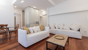 A modern living room with a glass dining table, two white sofas with cushions, and a wooden coffee table. - Italianway Comfort - Gherardini 2 (Milano)