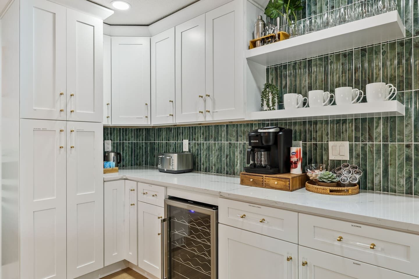 A kitchen with white cabinets, a coffee maker, a toaster, and a dish rack.