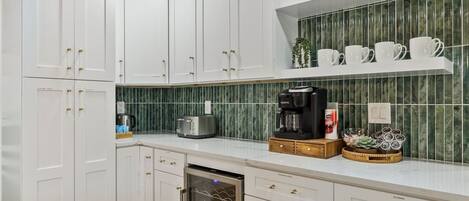 A kitchen with white cabinets, a coffee maker, a toaster, and a dish rack.