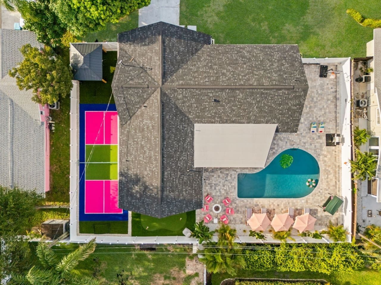 Vista aerea di una proprietà residenziale con piscina, area salotto all'aperto e campo da tennis.