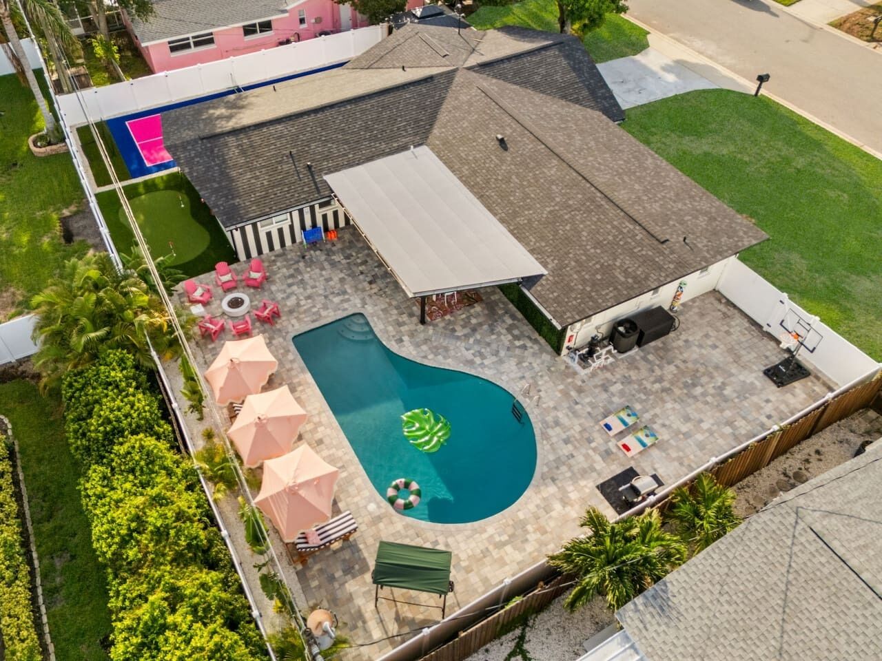 A residential backyard with a swimming pool, patio furniture, and a covered area.