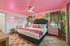 A bedroom with a bed, a nightstand, a chair, a ceiling fan, and a wall with a tropical mural. - Luxury Resort | Pool•Pickleball•Arcade•Karaoke (Seminole)