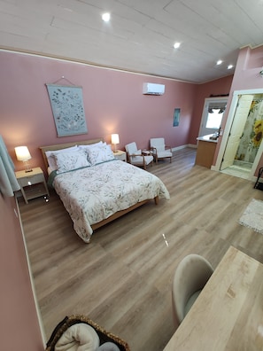 A bedroom with a bed, two chairs, a desk, and a mirror.