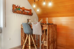Zona de bar con madera, una botella de vino, vasos y una silla.