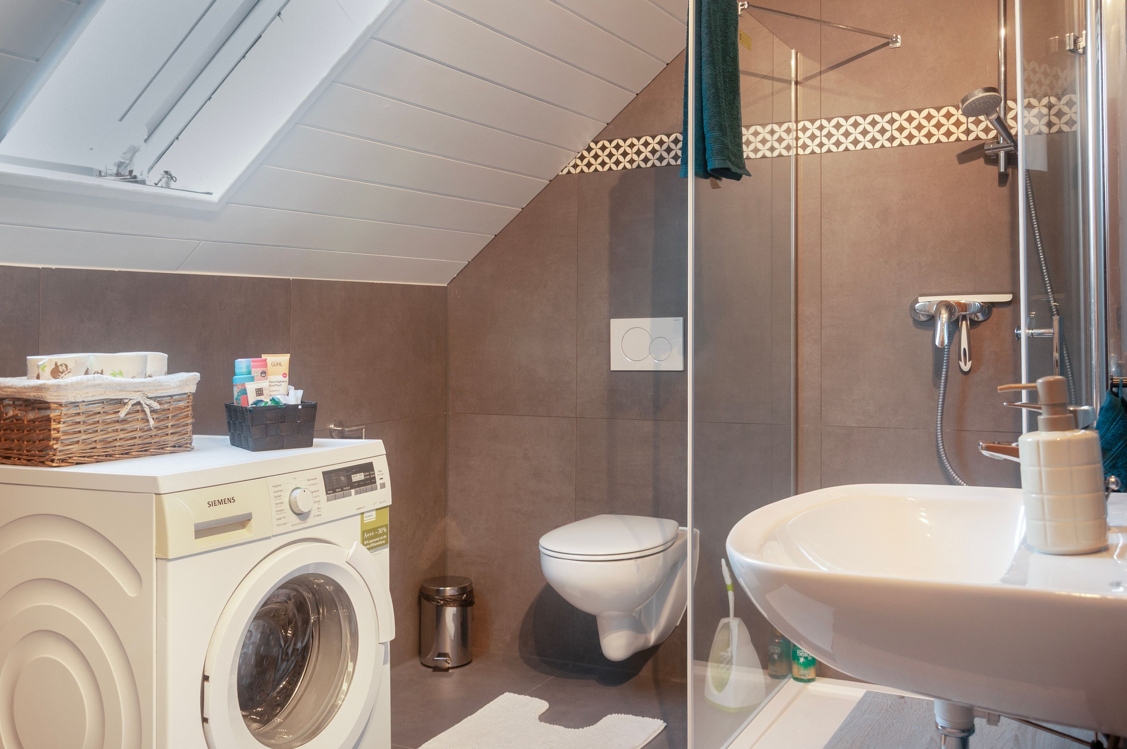 Ein kleines Badezimmer mit Waschmaschine, Toilette und einer Duschkabine.