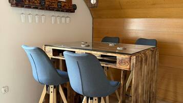 Comedor con mesa de madera, dos taburetes de bar y una lámpara colgante.