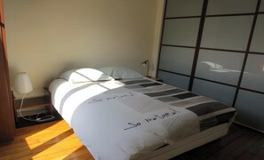 A bed with a white and black striped blanket, a lamp, and a window with a view of a building. - THE TIMELESS ELEGANCE OF A TRADITIONAL HAUSSMANN RESIDENCE - RUE DESNOUETTES (Paris)