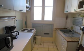 Une cuisine de taille réduite, équipée d’une cuisinière, d’un évier et de placards.
