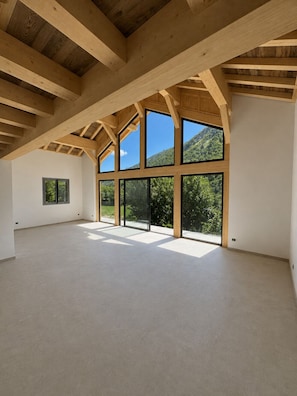 A spacious interior with high ceilings and large windows offering views of a mountainous landscape. - At Ginou - Jogidi Chalet (Saint-Sorlin-d'Arves)
