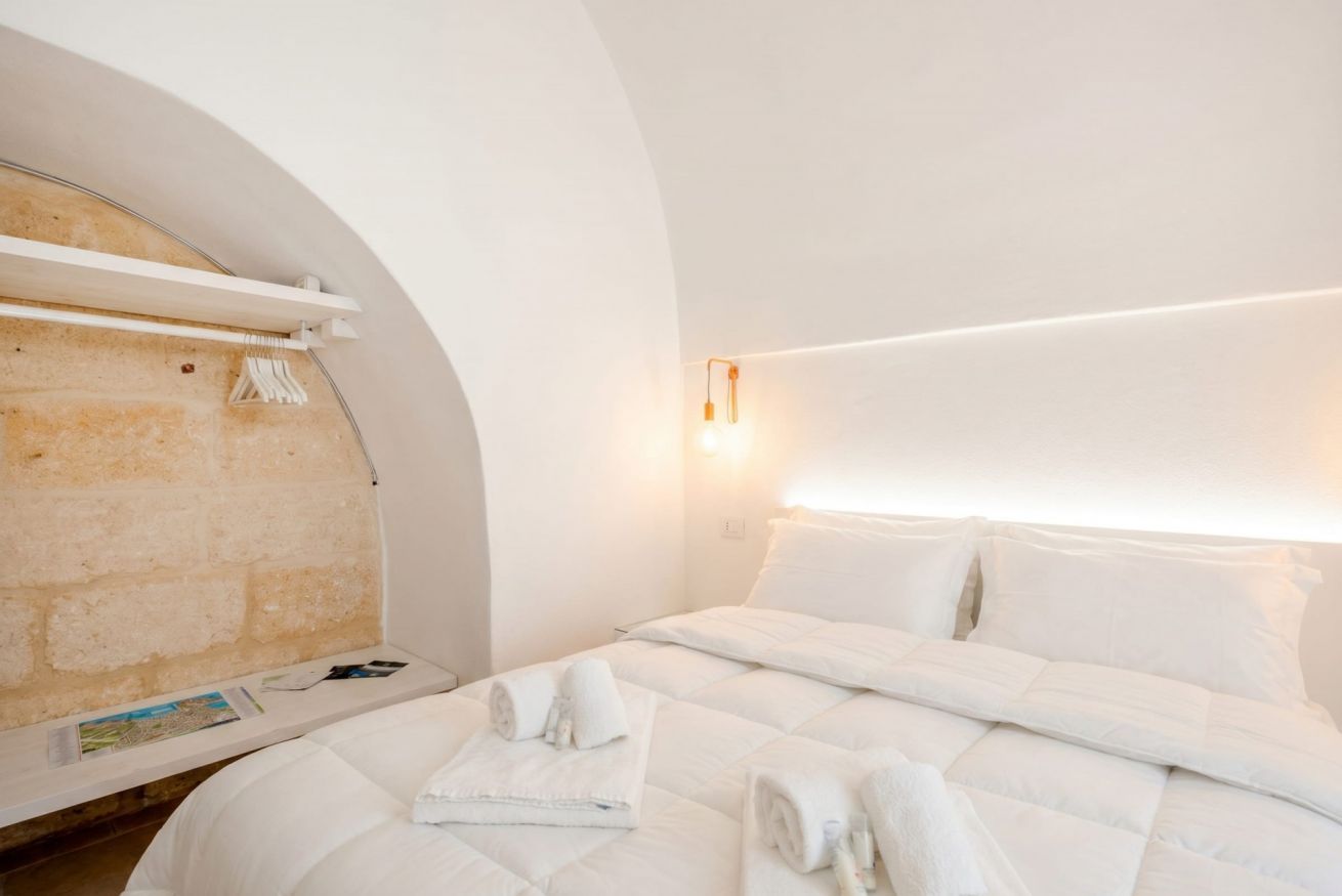 Ein Hotelzimmer mit Bett, Handtuchhalter, Wandleuchte und Steinwand.