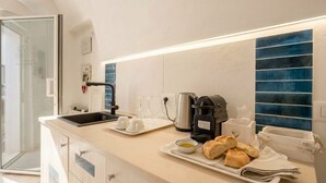 Uma cozinha moderna com cafeteira, pia e uma bandeja com pão e um recipiente de azeite.
