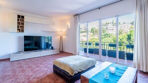 A modern bedroom with a large TV, a bed, and a balcony with a view. - Cubo's Casa Mediterranea BBQ & Terrace / near beach / free wifi (Málaga)