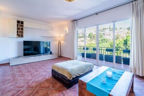 Un dormitorio moderno con una televisión grande, una cama y un balcón con vistas.