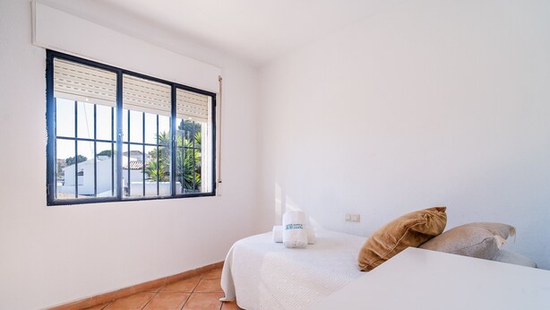 A bedroom with a bed, two pillows, a nightstand, and a window with blinds. - Cubo's Casa Mediterranea BBQ & Terrace / near beach / free wifi (Málaga)