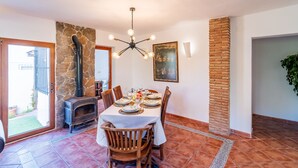 A dining area with a stone fireplace, a table set for four, and a hanging light fixture. - Cubo's Casa Mediterranea BBQ & Terrace / near beach / free wifi (Málaga)