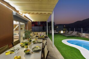An outdoor dining area with a pool, covered seating, and a view of the landscape. - Vista Golf 16 by VillaGranCanaria (Salobre golf resort)