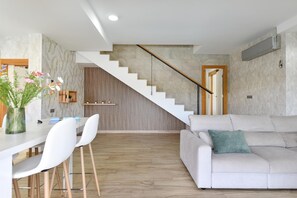A modern living space with a staircase, a dining area, and a sofa. - Vista Golf 16 by VillaGranCanaria (Salobre golf resort)