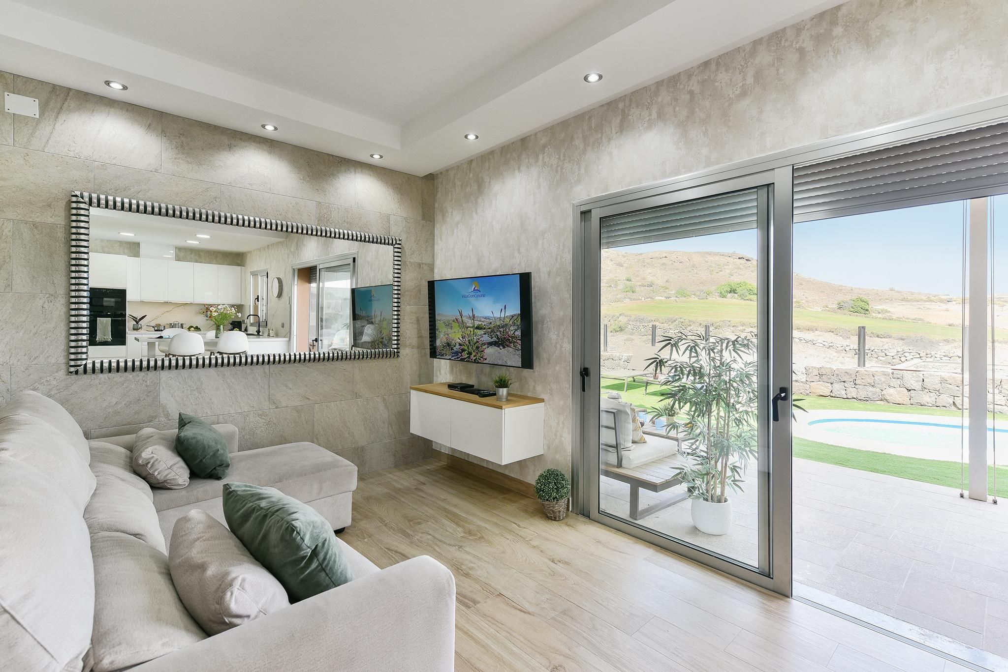 A modern living room with a sofa, a TV, and a sliding glass door leading to a patio.