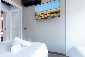 Ein Hotelzimmer mit einem Bett, einem an der Wand befestigten Fernseher und Blick auf eine Wüstenlandschaft.