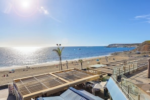 Blick auf einen Strand mit blauem Himmel, feinem Sand und Wasser.