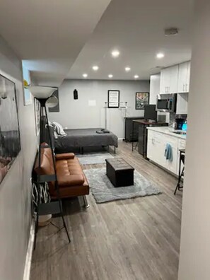 A compact living space with a bed, a sofa, a small kitchen area, and a dining table.