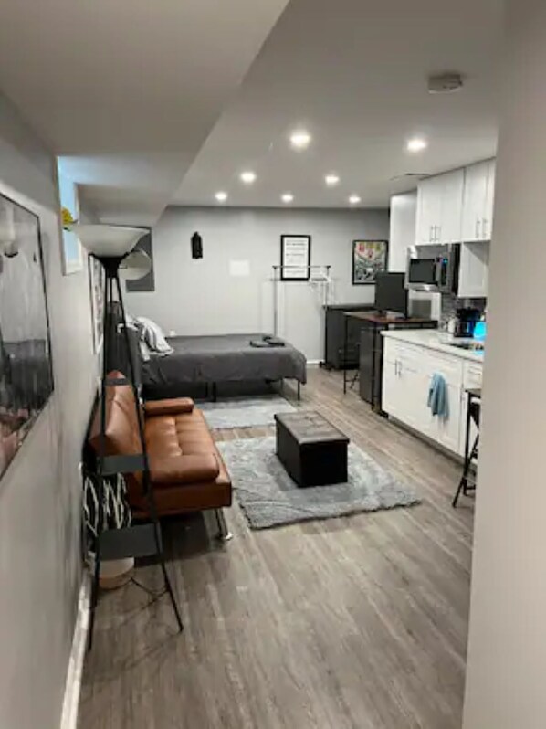 Un espacio habitable compacto con cama, sofá, pequeña cocina y mesa de comedor.