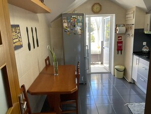 Eine Küche mit Esstisch, Stühlen, einem Kühlschrank und einer Wanduhr.
