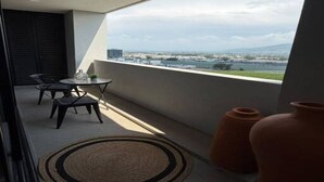 A balcony with a table and chairs, overlooking a cityscape.