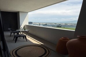 A balcony with a table and chairs, overlooking a cityscape.