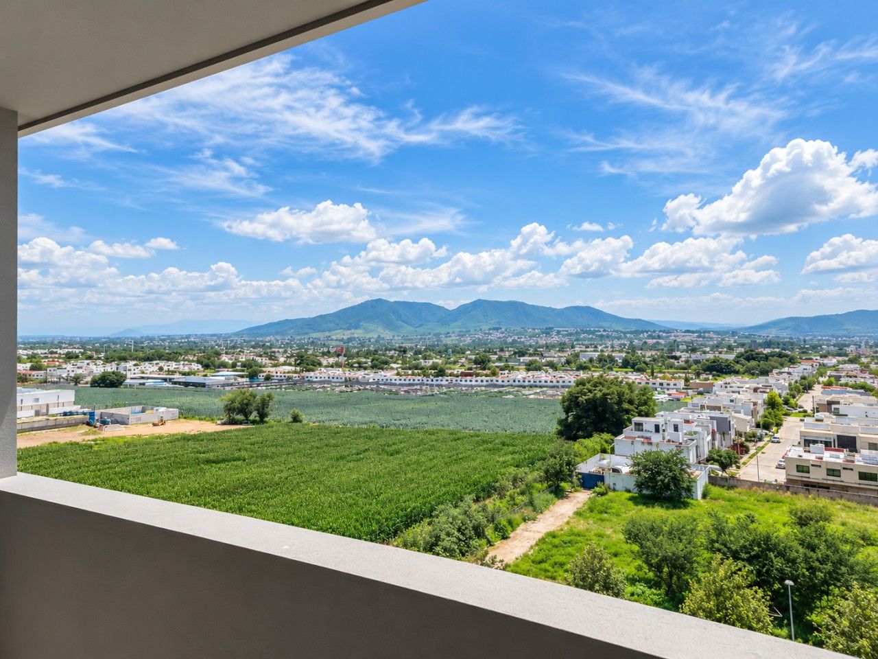 A view from a window overlooking a river, a town, and mountains.