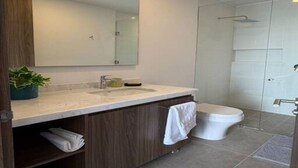 A modern bathroom with a large mirror, a sink, a toilet, and a shower area.