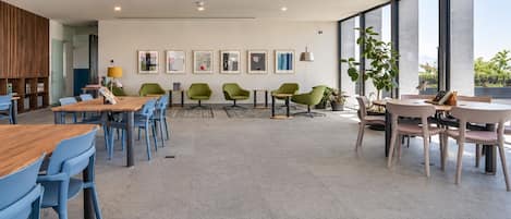 A modern dining area with wooden tables and blue chairs, a wooden slatted wall, and framed artwork on the wall.