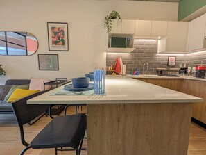 A modern kitchen with a central island, a dining area with chairs, and a living space with a sofa. - Amazing new loft in LEF habitat (Guadalajara)