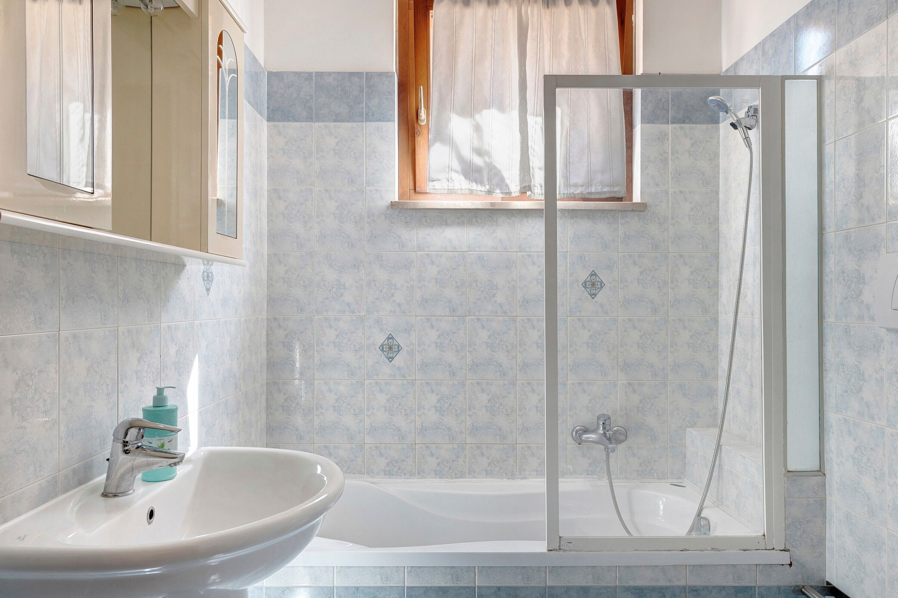 A bathroom with a shower, a sink, and a mirror.