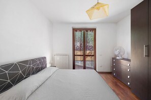 A bedroom with a bed, a dresser, a radiator, and a door leading outside.