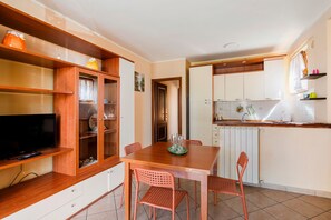 A compact kitchen with a dining area, wooden cabinets, and a television.