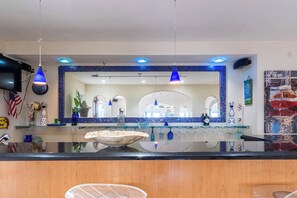 A modern kitchen with a large island, blue pendant lights, and a tiled backsplash. - Luxury 6BR Beach Front House In Fort Lauderdale (Fort Lauderdale)