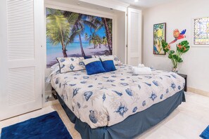 Ein Schlafzimmer mit einem Bett, einem Nachttisch, einer Topfpflanze und Bildern an den Wänden.